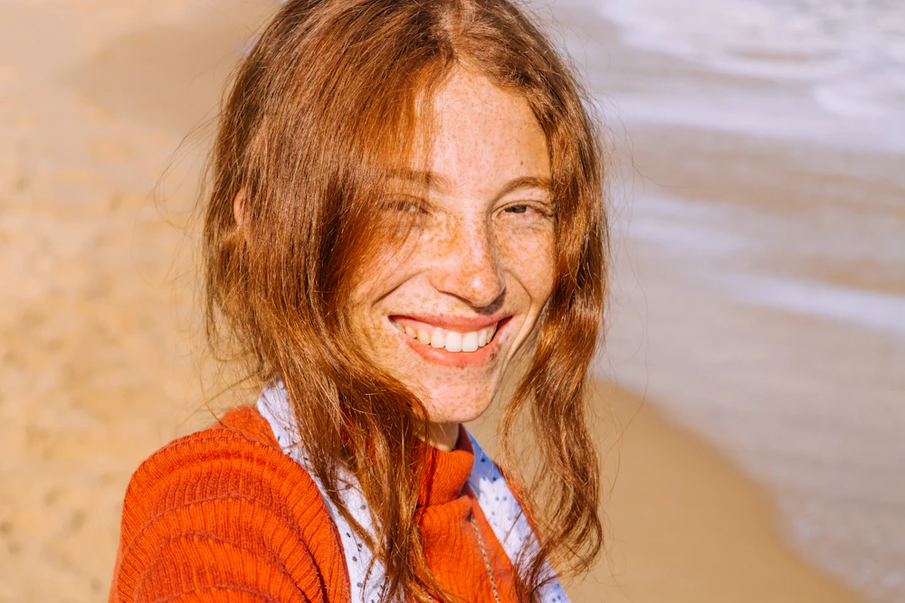 Young woman with red hair smiling in the sunshine