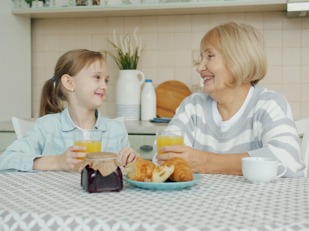 Grandmother and granddaughter smiling over breakfast